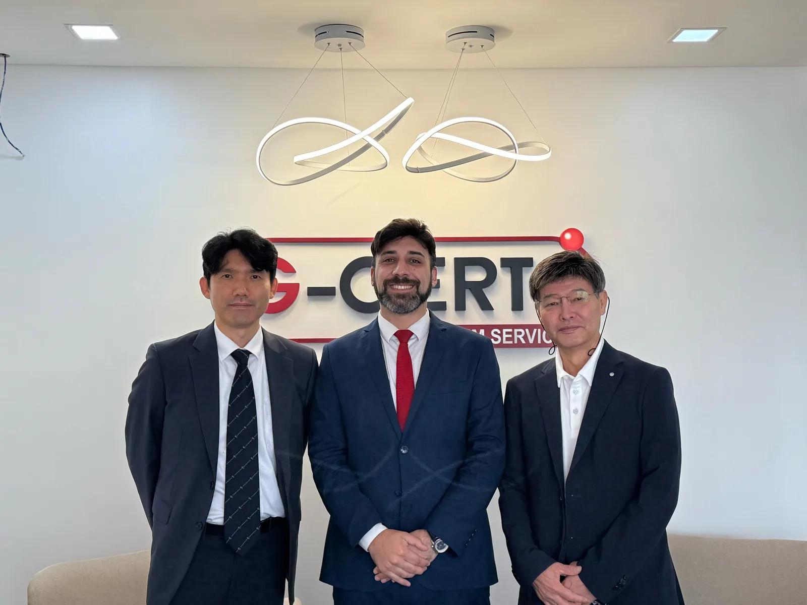 Fernando Arrieta junto a dos participantes frente al logo de G-CERTI